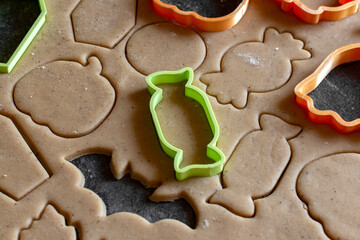 cookie cutter cuts gingerbread cookies out of dough for halloween