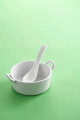 white soup cup and white spoon on green background