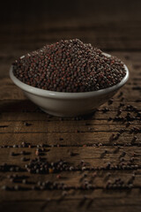 Black mustard seeds against a wooden background
