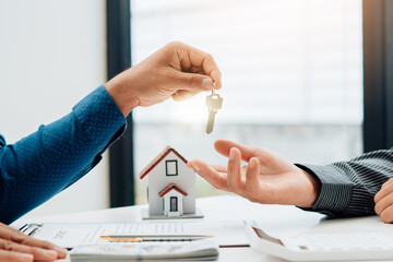 Real Estate Broker Or businessman holding white house model and house key in hand.Mortgage loan...