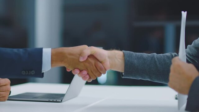 Professional Businessmen making handshake for deal, agreement and successful concept. Colleagues applauding in the background. Close-up shot.