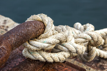 Fototapeta na wymiar Knotted rope at the dock. Sea port awaiting ships