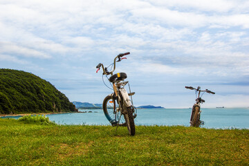 Landscape sea and mountains on the grassy edge of the beach with bicycles. Tourist view of cyclists during the halt at sunset.