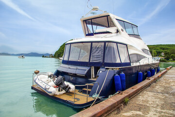 White ship on the sea in a rocky bay. Private motor ship on the background of misty mountains and forest shore