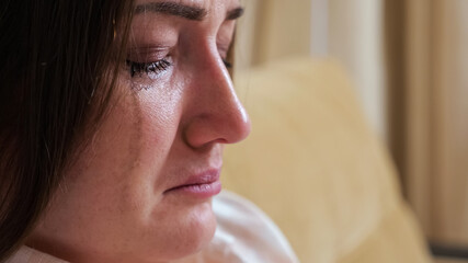 Close-up of a crying woman, blurry mascara dripping down her cheeks.
