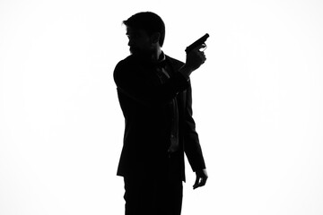 The man in a suit gun in the hands of the emotions silhouette light background