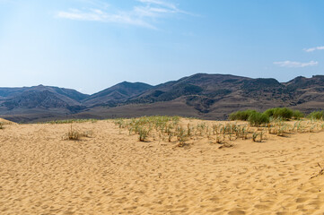 Picturesque Sarykum dune. Sandy mountain on the background of mountains, the Caucasus. Dagestan, Russia.