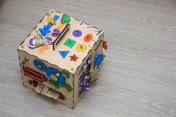 Wooden busycub for children's games. Education toy with colored details, rosette, clock, door, counts, toggle switches for kid