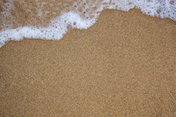 A crashing blue and green wave of water and sand on the ocean shore. Background for design with a splash and drops of spray