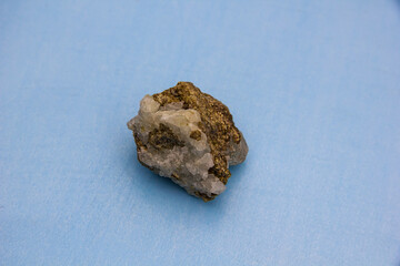 Geological untreated sample of rock mineral. Natural outgrowth of quartz on a blue background