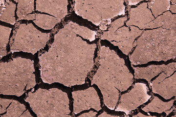 Cracked dry land during a drought. A long time without rain. Infertile red soil without plants