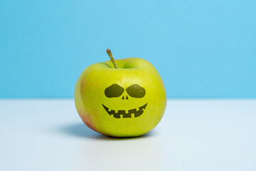 Ripe apple with an evil smile. Halloween holiday.
