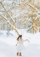 Fabulous girl walks on a forest path with a lantern in hand. Christmas time. Sunny winter day.