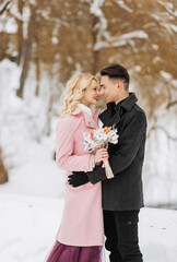 Happy couple hugging and laughing outdoors in winter. Couple embracing in snowy winter park.Winter wedding of stylish beautiful young couple bride and groom