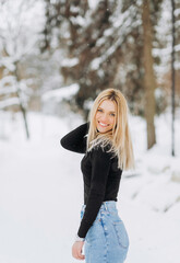 Fototapeta na wymiar Stylish blonde in baggy jeans posing in a winter park.