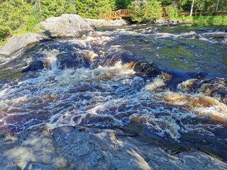 View of the bubbling waterfall with brown water on the Tokhmayoki River in Karelia from the...