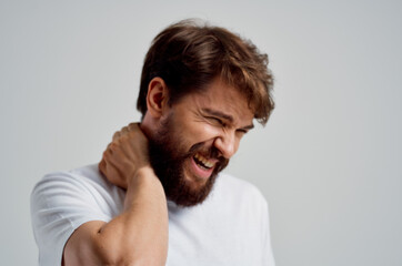 Obraz premium emotional man in a white t-shirt stress medicine pain in the neck light background