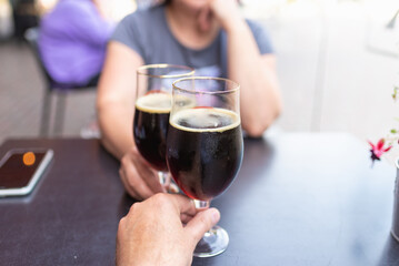 Woman and man drink beer. Friends met in a pub. Two glasses of dark beer.Two people toasting with glasses of beer.