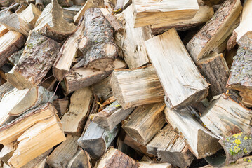 Fuel and heat source for the winter season.Preparing for the firewood heating season. Chopped firewood of different trees,outdoors.