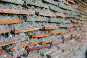 Red tile wall with gray cement in the distance perspective. Clay tile shingles horizontally in exterior wall. Architecture. Selective focus. No people.