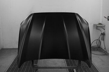 Car maintenance station. Car repair. The painted hood of the car is fixed in a special white box.