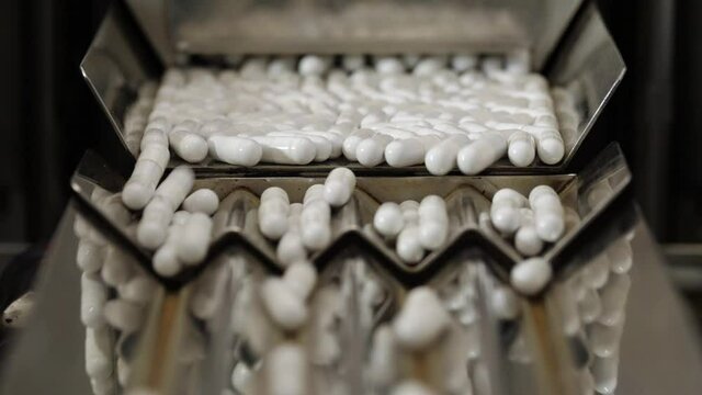 Pharmaceutical production. Medical capsules are moving in a packaging machine. Slowmotion 120 fps.