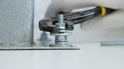 Constructor Screwing a Nut onto a Metal Screw and Tightly Secure a Part of a Mechanical Assembly