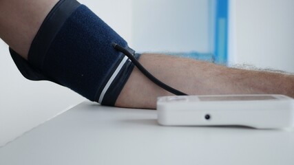 Elderly Person in Hospital Measuring His Blood Pressure with an Electronic Device