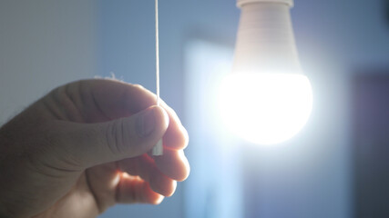 Image with a Man Switching ON a LED Bulb in a Room.