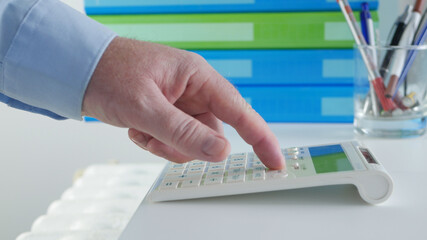 Businessman Working with Invoices, Makes Financial Calculations with Adding Machine. Accounting Fee and Taxes Calculations.