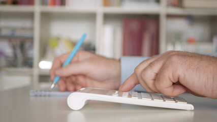 Businessman Working with Invoices, Makes Financial Calculations with Adding Machine. Accounting Fee and Taxes Calculations.