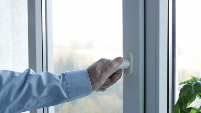 Image with a Hand Opening a Window in Office Room