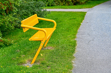 yellow painted metal bench in public park
