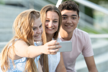 Happy teenager friends taking a selfie sitting on stairs.