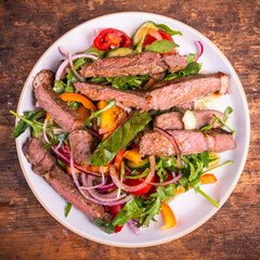 Thai salad with vegetables and pieces of beef steak, portion on a plate, top view