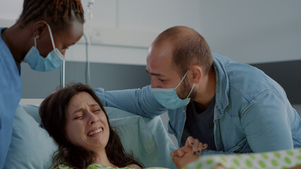 Caucasian pregnant woman giving birth to child in painful labor. Young patient pushing for baby...