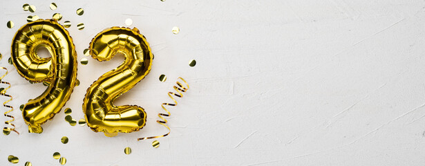 golden foil balloon number ninety two. Birthday or anniversary card with the inscription 92. gray...