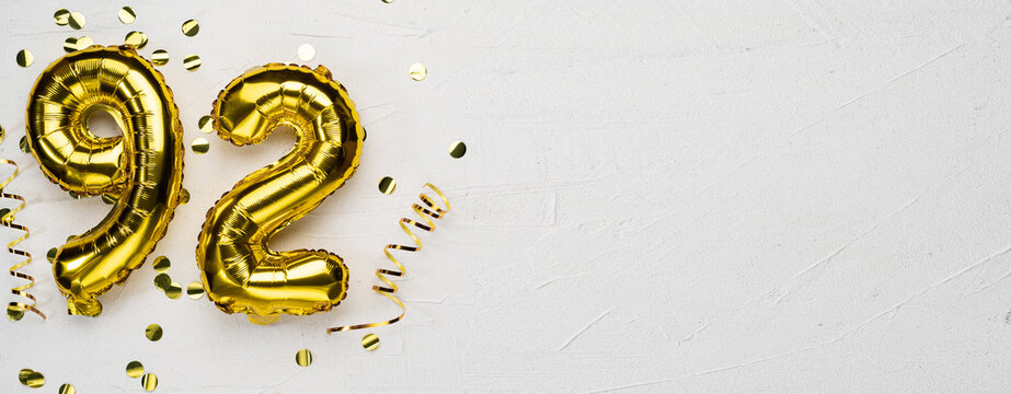 golden foil balloon number ninety two. Birthday or anniversary card with the inscription 92. gray concrete background.