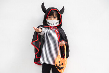 Asian little girl in a Halloween costume in a medical mask . Halloween with safety measures from Covid-19
