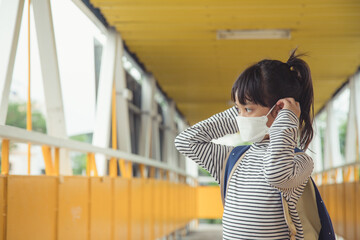School child wearing a face mask during coronavirus and flu outbreak. Little girl going back to school after covid-19 quarantine and lockdown.
