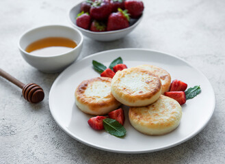 Cottage cheese pancakes, ricotta fritters on ceramic plate with  fresh strawberry.