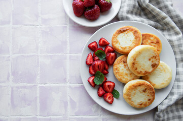 Cottage cheese pancakes, ricotta fritters on ceramic plate with  fresh strawberry.