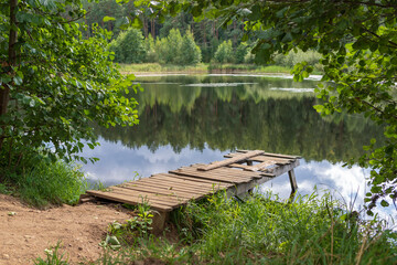 Idyllic view of the wooden pier in the lake with forest background. Pier in the lake. Beautiful lake in the forest.