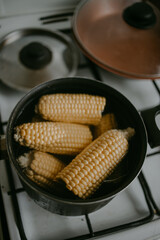 cooking the corn at the saucepan on the kitchen