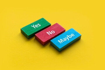 Yes, No and Maybe wooden block on a yellow background.