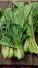 Obraz premium Photo of several bunches of mustard greens being sold on a wooden table