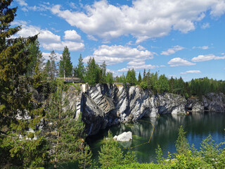 View of the rocks and the emerald water of the Marble Canyon in the Ruskeala Mountain Park, which reflects the sky and rocks on a sunny summer day.