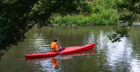 Traveler with paddle and kayak on a small river