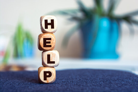 The inscription HELP on wooden cubes on a light background, on the table top view.