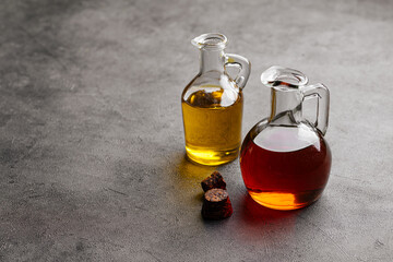 Side view on two lass jugs with oil for cooking on a grey background